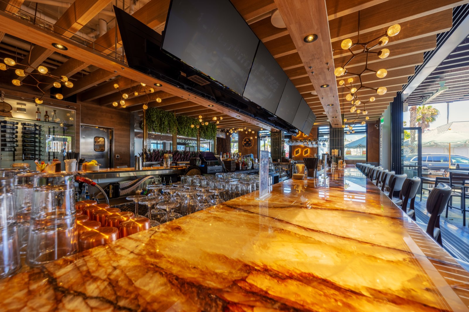 The backlit onyx bar with rows of glassware at Bier Garden Oceanside
