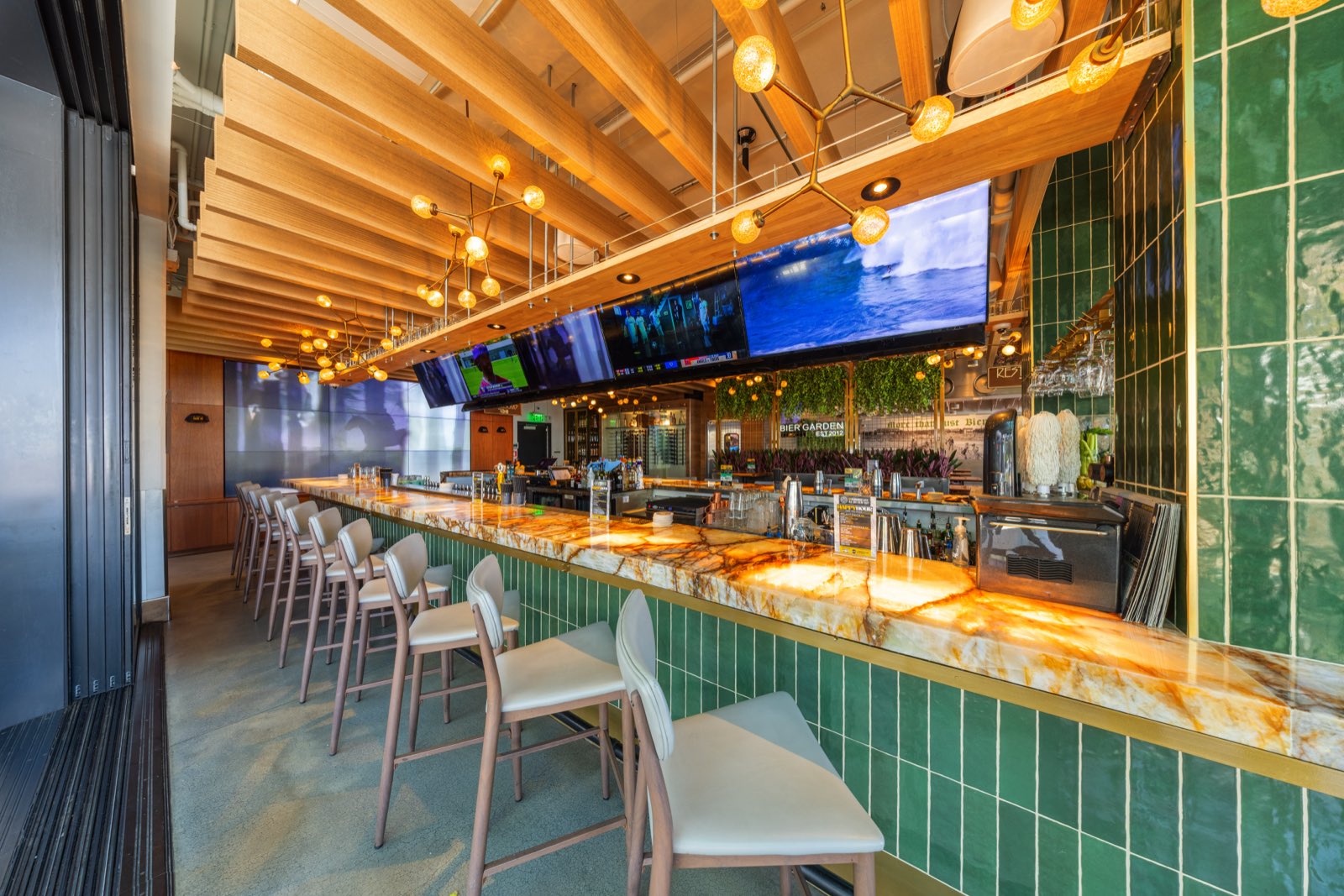 Bar rail with glowing onyx counter and game-day screens