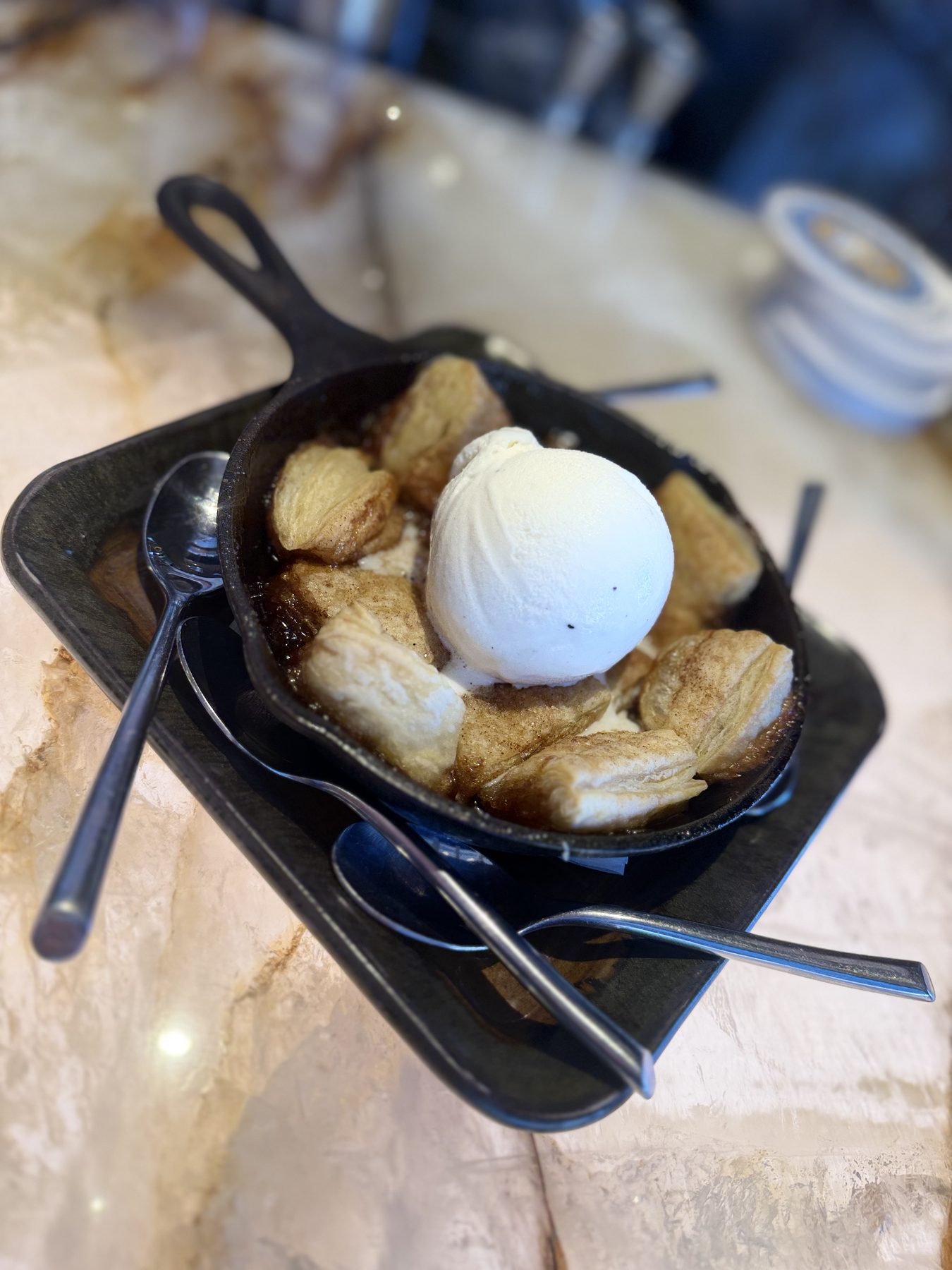 Cast-iron skillet dessert of golden cinnamon-sugar biscuits topped with a scoop of vanilla ice cream
